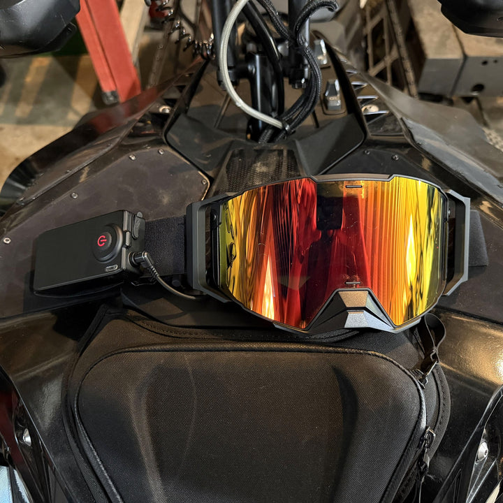 Hillarie heated snowmobile goggle with the battery pack, resting on a snowmobile #strap_top-secret-1